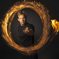 Comedy Juggler Paul Isaak, surrounded by a ring of fire, during a stage show